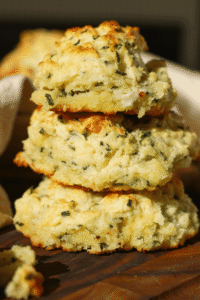 These cheddar chive cathead biscuits are packed with sharp cheddar cheese and fresh chives, with soft, flaky layers in every bite. This easy homemade biscuit recipe skips rolling and cutting—just scoop, bake, and serve!